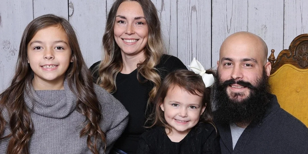 Brett, owner of Steel Valley Fire Protection, smiling with his family in a studio portrait against a gray wood-paneled background.