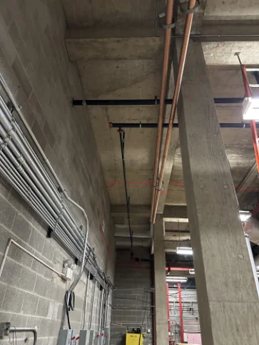 Overhead fire protection main lines and structural pipe routing.