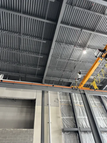 Precision fire sprinkler line installation along structural steel beams.