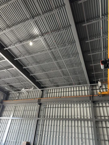 Warehouse fire sprinkler system integrated into corrugated steel ceiling structure.